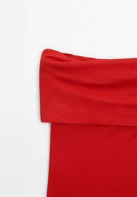 Haut rouge tombe sur les épaules en tissu doux avec un décolleté drapé et une silhouette ajustée, présentant une texture lisse et une teinte vive.
