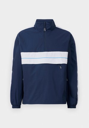 Marineblå genserjakke med høy krage, med en hvit horisontal stripe og lyseblå detaljer over brystet. Elastiske ermer.