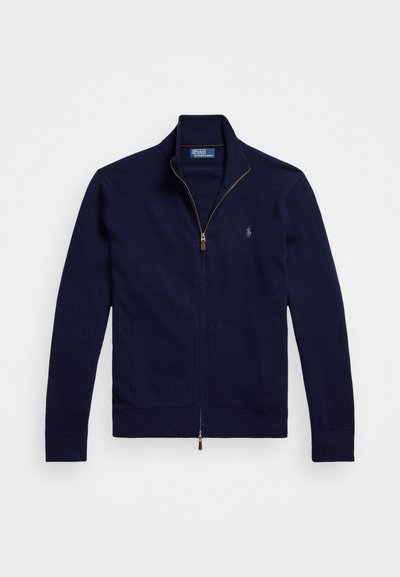 Granatowy sweter z zamkiem błyskawicznym, wykonany z miękkiej dzianiny. Posiada wysoki kołnierz, dwie przednie kieszenie oraz małe haftowane logo na piersi.