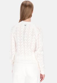 Pull blanc en maille avec un motif texturé à tissage ouvert. Comprend des poignets et un ourlet côtelés, avec un petit logo à l'arrière du col.