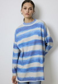 Overmaat trui in crèmekleur met blauwe horizontale strepen. Heeft een ribbelhals en boorden, een zachte textuur en een relaxte pasvorm.