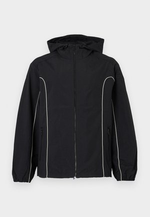 Musta tuulitakki valkoisilla saumoilla, etupuolella täysipitkä vetoketju, säädettävä huppu, joustavat hihansuut ja sivutaskut. Sileä kangaspinta.