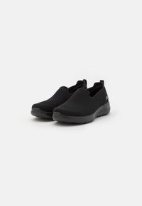 Ballerines en mesh noir à bout rond, avec une surface texturée, une semelle flexible et une petite boucle à l'arrière pour un enfilage facile.