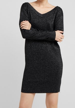 Robe en tricot noire à manches longues, décolleté en V large et texture pailletée. Design de longueur hanches avec fentes latérales pour faciliter les mouvements.