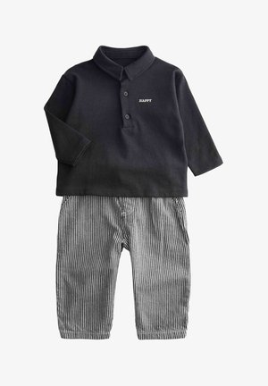 Polo nero a maniche lunghe con colletto e tre bottoni, con la scritta "HAPPY". Abbinato a pantaloni a righe bianche e nere.