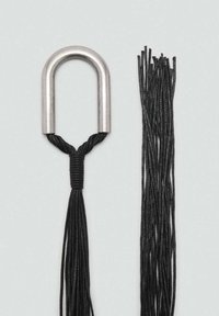 Poignée en métal en forme de U reliée à des cordes tressées noires, avec de longs brins fins s'étendant vers l'extérieur, sur un fond gris clair.