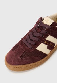 Baskets en daim bourgogne avec des accents crème, dotées d'un mesh synthétique, d'une semelle en caoutchouc, de lacets plats et d'un logo sur la languette et le côté.