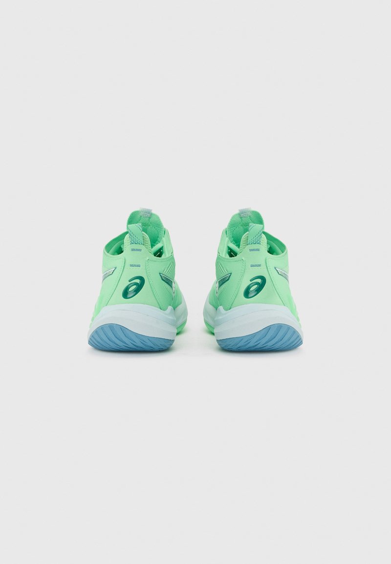 Paire de chaussures de sport vert menthe avec semelles bleues, vue de dos, montrant des languettes de traction au talon et des logos de marque.