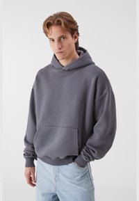 Grå hættevest med en frontlomme, ribbede manchetter og kant. Lavet af blødt stof, med en afslappet pasform og minimalistisk design.