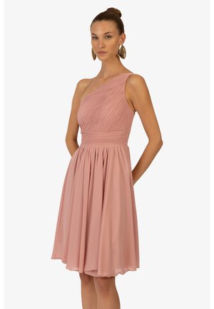 Ein schulterfreies Kleid aus weichem pinkfarbenem Chiffon, mit plissiertem Oberteil, tailliertem Schnitt und einem fließenden Rock, der oberhalb des Knies endet.