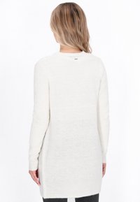 Maglione bianco lungo leggero a maglia con colletto rotondo, polsini a costine e spacco laterale. Texture morbida e vestibilità leggermente oversized.
