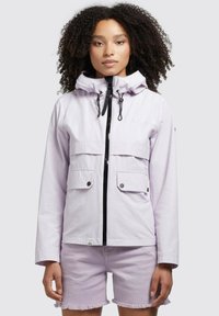 Jachetă zip-up de culoare violet deschis, cu două buzunare frontale, glugă ajustabilă și fermoar negru. Purtată cu pantaloni scurți asortați de culoare lavandă.