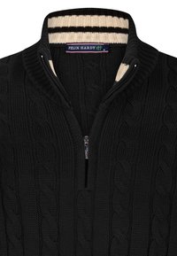 Schwarzer Strickpullover mit einem Viertel-Reißverschluss, der ein Kabelstrickmuster aufweist. Der Kragen hat abwechselnde cremefarbene und braune Streifen. Markenetikett sichtbar.
