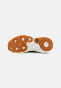 Shoe sole with a textured white and orange rubber. Features circular patterns and various raised elements for traction.