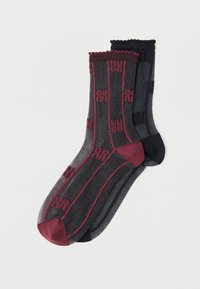 Δύο ζευγάρια διαφανείς κάλτσες με μοτίβο, το ένα μαύρο με μπορντό λεπτομέρειες και το άλλο σκουρόγριζο με μαύρες λεπτομέρειες, τοποθετημένα επίπεδα σε λευκό φόντο.