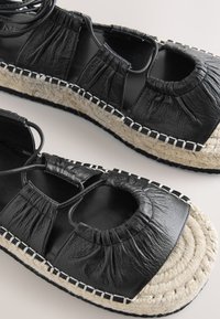 Sorte læderespadrillesandaler med rynkede detaljer, åben tå og sål indpakket i jute. Har kontrastsyede detaljer.