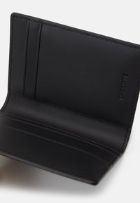 Portefeuille en cuir noir avec plusieurs emplacements pour cartes, texture lisse et bords surpiqués ; présente le logo de la marque embossé à l'intérieur.
