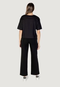 Camiseta negra corta de manga corta, combinada con pantalones anchos negros y zapatos de plataforma blancos con un acento decorativo negro.