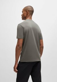 Korte ermers, rund hals t-skjorte i mørkegrå, med en glatt tekstur og minimalistisk design. Bakre visning viser en avslappet passform og enkel konstruksjon.