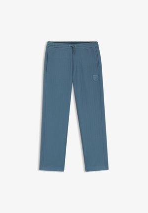 Light blue athletic pants with a drawstring waistband, vertical ribbed texture, side pockets, and a prominent logo patch on one leg.