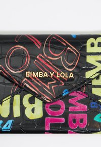 Czarny portfel o teksturowanej powierzchni z kolorowym tekstem w stylu graffiti oraz złotym logo. Projekt kopertowy ma spiczasty klapek i błyszczące wykończenie.