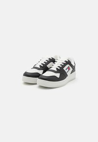 Sneaker in bianco e nero con esterno in pelle liscia, punta perforata e design con lacci. Presenta un dettaglio del logo sul lato. Suola in gomma.