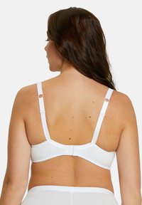 Witte beha met verstelbare schouderbanden en haak-en-oog sluiting aan de achterkant. Gladde stof met geschulpte randen langs de band.