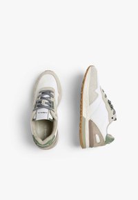 Zapatillas deportivas con una parte superior de cuero blanco y detalles en ante gris y verde, cordones grises y una suela de goma texturizada.