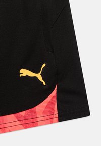 Schwarze Sportshorts mit einem pinken grafischen Einsatz am unteren Rand und einem gelben springenden Katzenlogo an der Seite. Glattes, synthetisches Material.