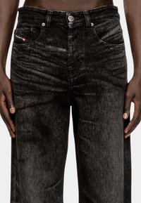 Pantaloni in denim neri con una finitura testurizzata, caratterizzati da un design a gamba dritta, tasche frontali e hardware in metallo argentato.