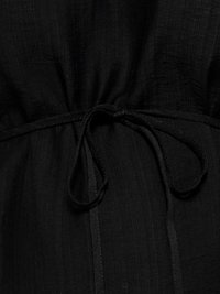 Tie detail in black fabric gathered at the waist, showing texture and stitching on a garment.