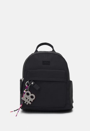 Sac à dos noir en nylon avec une forme arrondie, fermeture éclair, poche avant et un charm coloré attaché. Comprend une poignée supérieure et des bretelles réglables.