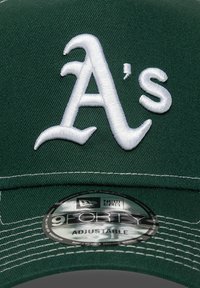 Gorra de béisbol verde con logotipo bordado en blanco de "A's", material texturizado, correa ajustable y etiqueta circular New Era 9FORTY en el interior.