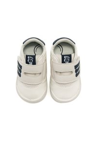 Scarpine per bambini in pelle bianca con forma rotonda, dettagli blu navy e due cinturini in velcro. Sole texturizzata per una migliore aderenza, con una grafica di un piede all'interno.