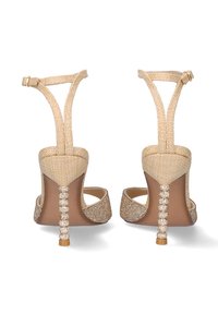 Sandalias de tacón alto beige con correa ajustable, parte superior de tejido texturizado y tacones adornados con brillantes que presentan un patrón de gemas transparentes.