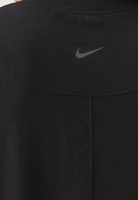 Czarny sportowy strój z wysokim kołnierzem, gładką fakturą i odblaskowym szarym logo Nike umieszczonym na środku pleców.