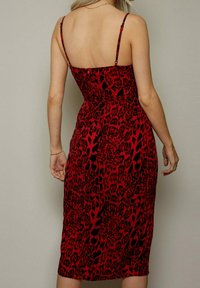 Rotes Midi-Kleid mit Leopardenmuster, dünnen verstellbaren Trägern, figurbetontem Oberteil und weicher Textur, mit einer glatten, fließenden Silhouette.
