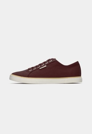 Burgundy canvas sneakers with a rounded toe, white rubber sole, and six eyelets. Minimalistic design with a subtle logo accent.