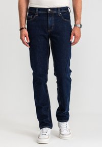 Ciemnoniebieskie jeansy denimowe o prostym kroju, z pięcioma kieszeniami i kontrastującym pomarańczowym przeszyciem. Wyposażone w zapięcie na guziki i szlufki na pasek.