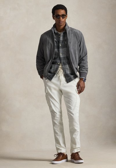 Γκρι σουέντ μπουφάν, πουκάμισο με καρό σχέδιο, κρεμ παντελόνι cargo, καφέ αθλητικά παπούτσια με κορδόνια και γυαλιά ηλίου. Ομαλές υφές και άνετη εφαρμογή.