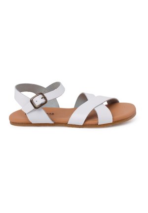 White cross-strap sandals made of synthetic material with a padded brown insole and a buckle on the adjustable ankle strap.