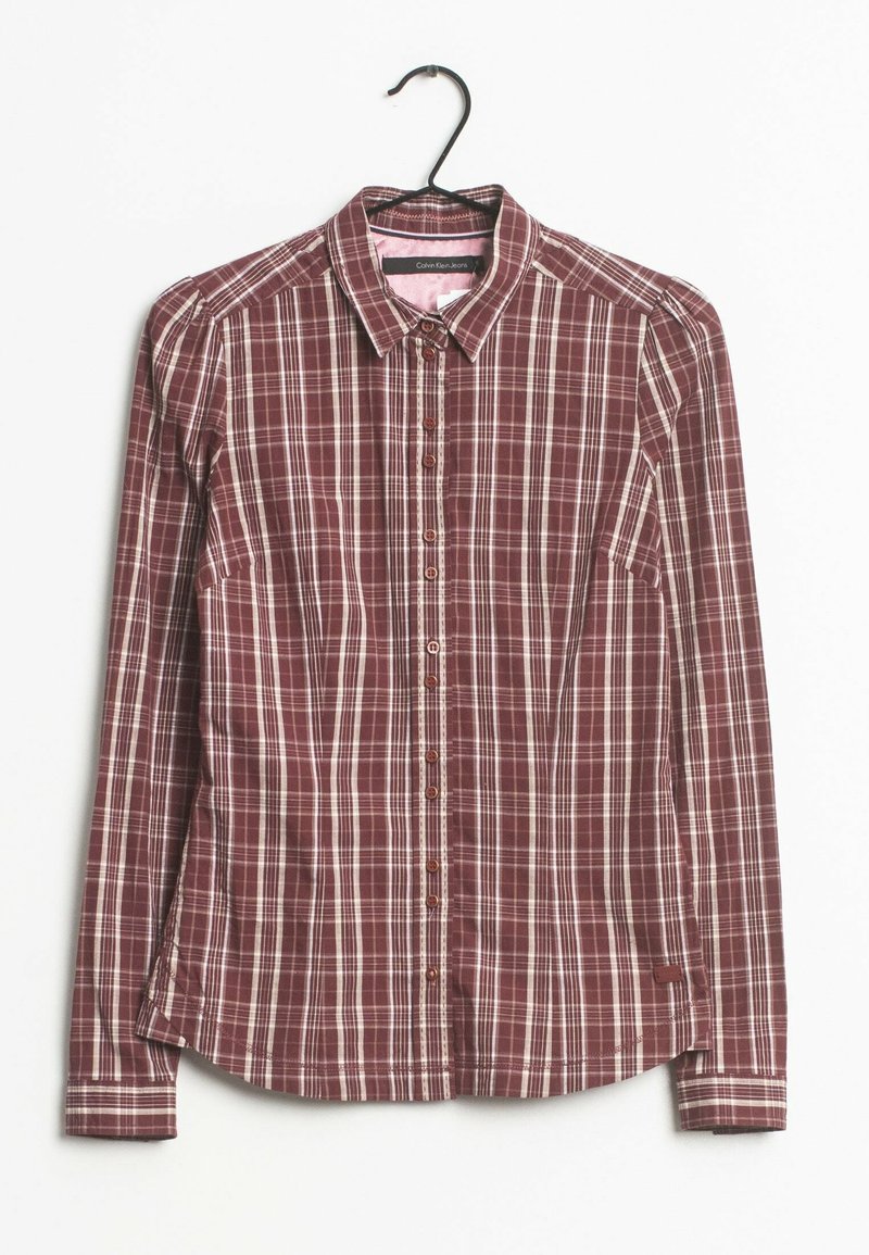 Chemisier pour femme à manches longues avec motif à carreaux rouge et blanc, col pointu et silhouette ajustée sur un cintre noir.