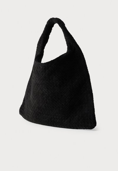 Μαύρη πλεκτή τσάντα ώμου με μία λαβή, μαλακή υφή και χαλαρή, τριγωνική μορφή σε απλό φόντο.