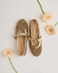 Zapatos de color dorado con un diseño Mary Jane, que cuentan con una superficie texturizada adornada con pequeños remaches y una correa a juego.