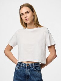 Bílý bavlněný zkrácený tričko s kulatým výstřihem a krátkými rukávy, ve spojení s vysoce pasovými zesvětlenými modrými džíny s viditelným knoflíkem.
