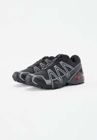 Black running shoes with gray accents, mesh upper, textured sole, and quick-lace system. Features a logo and reinforced toe cap.
