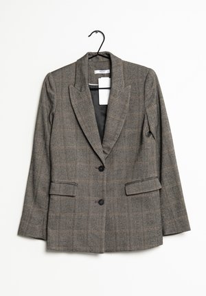 Blazer grigio a quadri con due bottoni, colletto a lancia e tasche con pattina appeso a una gruccia nera su sfondo bianco.