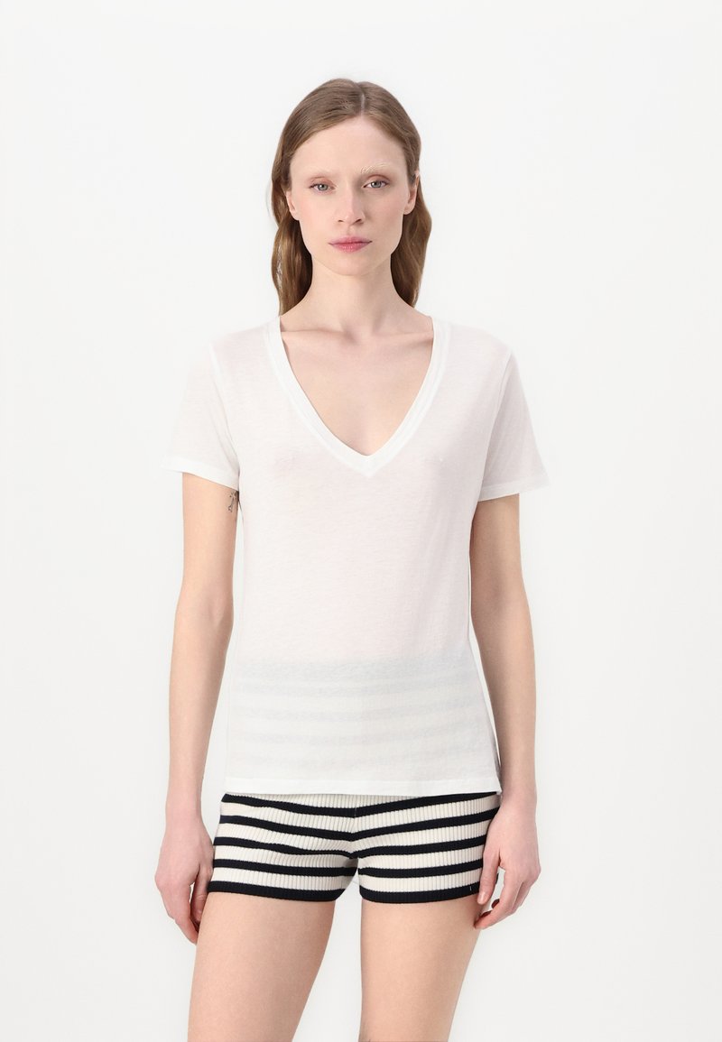 Hvid kortærmet V-hals t-shirt med en blød tekstur, parret med marineblå og cremefarvet stribede ribbede shorts. Minimalistisk design med en afslappet pasform.