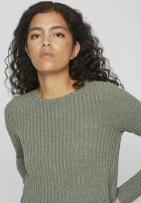 Pull en maille côtelée à manches longues dans un vert doux. Texture douce avec un col rond et une silhouette ajustée. Le tissu a un léger éclat.