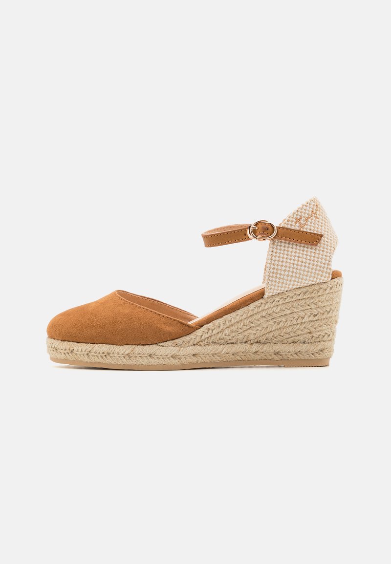 Sandal de cuña de ante marrón con suela de yute trenzado, tira en el tobillo y acento de tela a cuadros en el tacón. Diseño de punta redondeada y escote bajo en el vampiro.